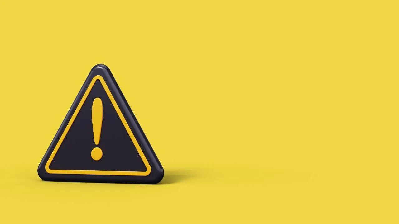 A black triangular warning sign with a yellow exclamation mark stands on a yellow background, with ample empty space on the right side.