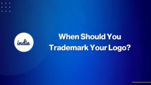 Blue background with the word indie in a white circle on the left and the text When Should You Trademark Your Logo? in bold white font in the center.