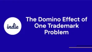A blue slide with white text that reads “The Domino Effect of One Trademark Problem.” On the left, there is a white circle with the word “indie” written inside in dark blue script.