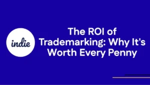 A blue background with the word indie in a white circle on the left. The text reads: The ROI of Trademarking: Why Its Worth Every Penny. Thin yellow line graphics are at the bottom right.