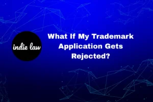 A graphic with the indie law logo and the text "What If My Trademark Application Gets Rejected?" on a blue background with geometric lines, guiding you on next steps if your trademark application isn’t approved.