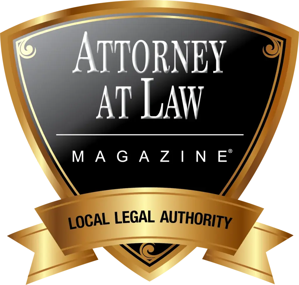 A gold and black shield-shaped badge reads "Attorney at Law Magazine" with a gold ribbon below stating "Local Legal Authority.