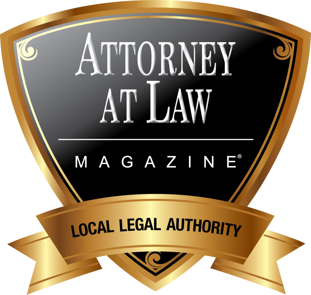 A gold and black shield-shaped badge reads "Attorney at Law Magazine" with a gold ribbon below stating "Local Legal Authority.