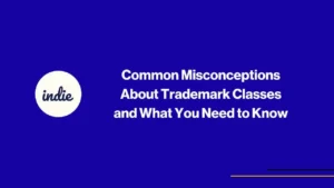 Dark blue background with white text: Common Misconceptions About Trademark Classes and What You Need to Know. A white circle on the left contains the word indie in lowercase. Thin yellow and purple lines at the bottom right.