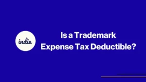 Blue background with white text that reads: Is a Trademark Expense Tax Deductible? and a white circle on the left with the word indie inside. There are two thin yellow lines in the bottom right corner.