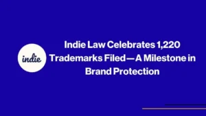 Image with a blue background featuring the text: Indie Law Celebrates 1,220 Trademarks Filed—A Milestone in Brand Protection. A white circle with the word indie is on the left. Thin yellow and purple lines are at the bottom right.