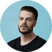 A man with short brown hair and a trimmed beard wearing a black shirt, known for his expertise in trademarks, looks at the camera against a light blue background.
